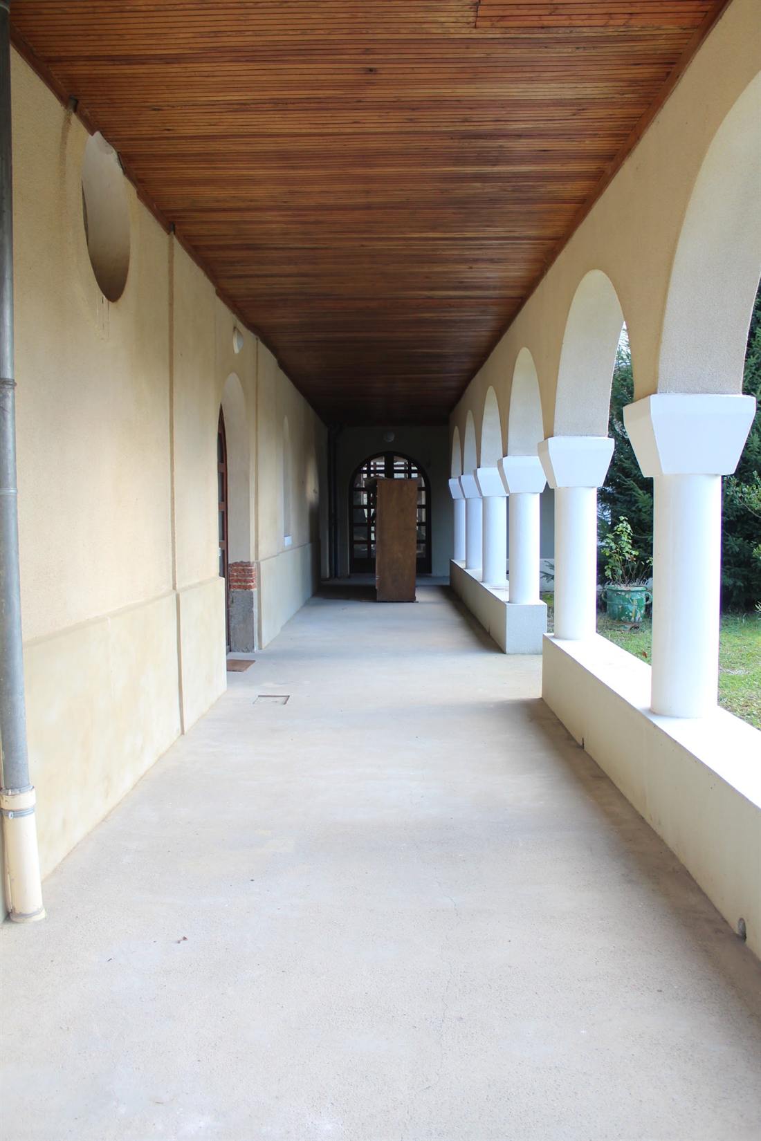 A covered gallery of the abbey, white arcades on the garden